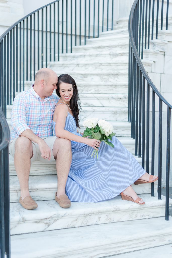 engaged couple sit on white marble stairs
