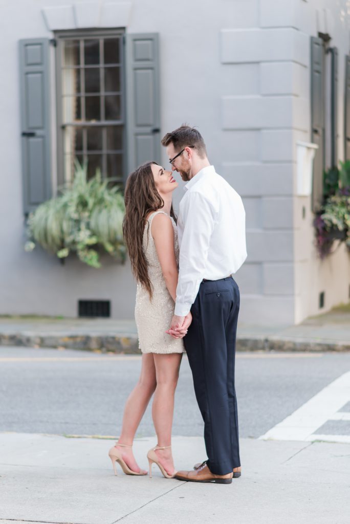 Engaged couple stand hand in hand on street corner