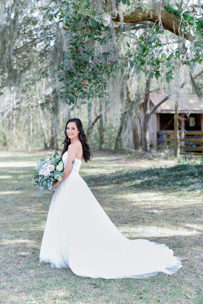 bride standing on horse farm with large pastel bouquet