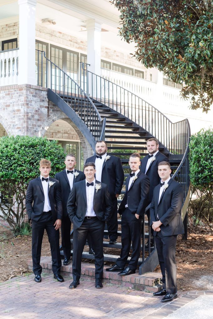 Groomsmen posing on back stairs of Dunes West Country Club