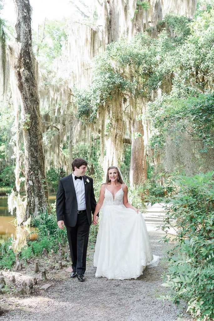 newlyweds walk hand in hand at Magnolia Plantation