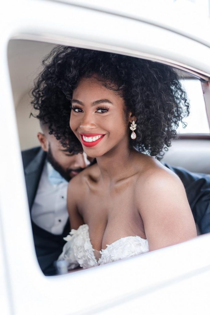 beautiful bride smiles through window of get-away car