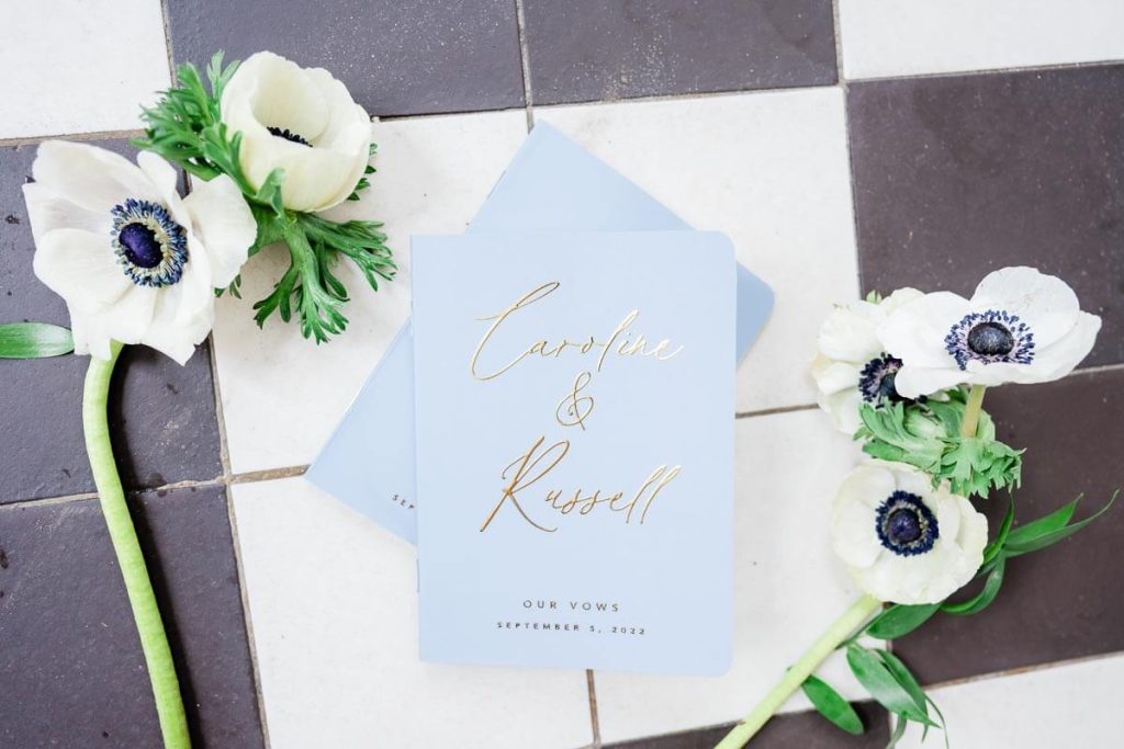pale blue vow books on floor with flowers