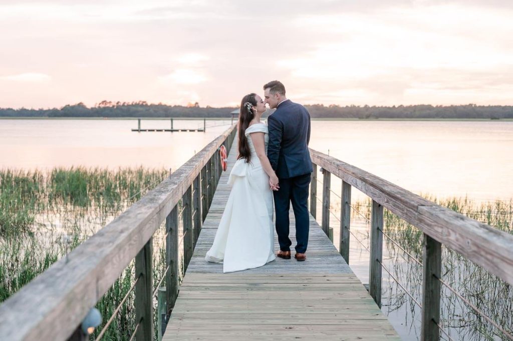 newlyweds nuzzle on dock during sunset