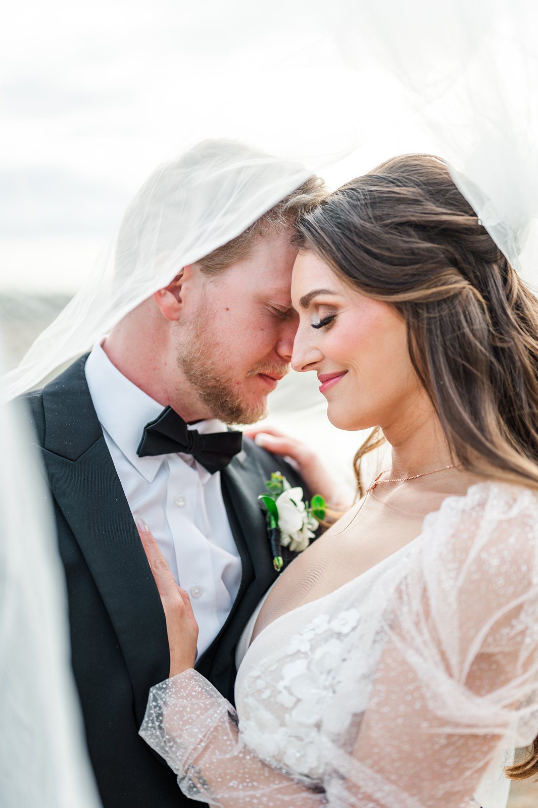 Newlyweds nuzzle under bride's veil