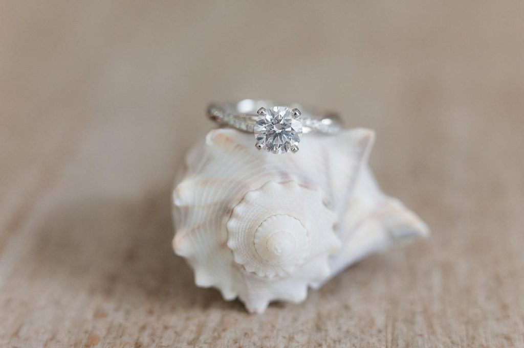 close up of engagement ring on seashell