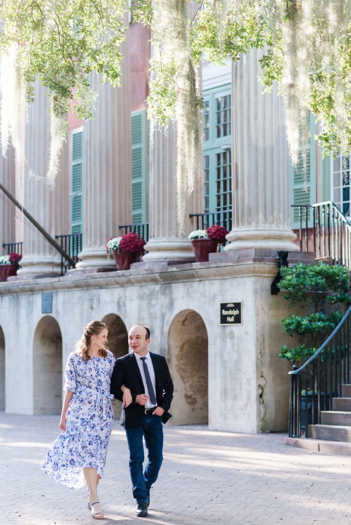 engaged couple walk arm in arm on College of Charleston campus