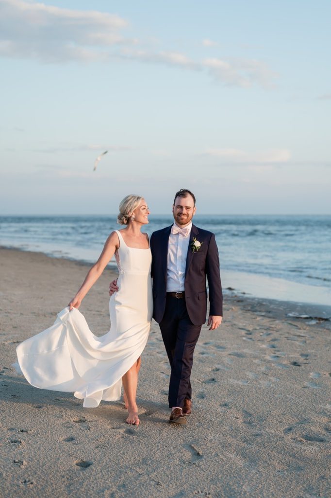 newlyweds walk on beach at sunset