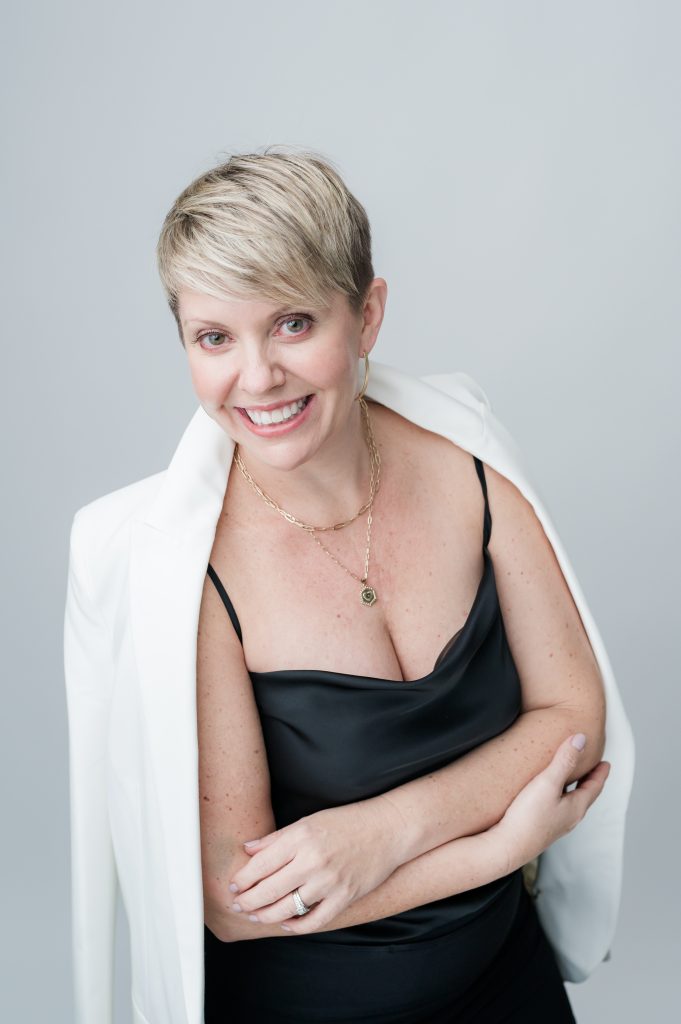 woman stands crossing arms with white jacket over shoulders