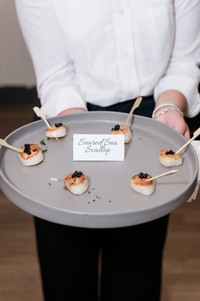 waitress holding platter of seared sea scallops