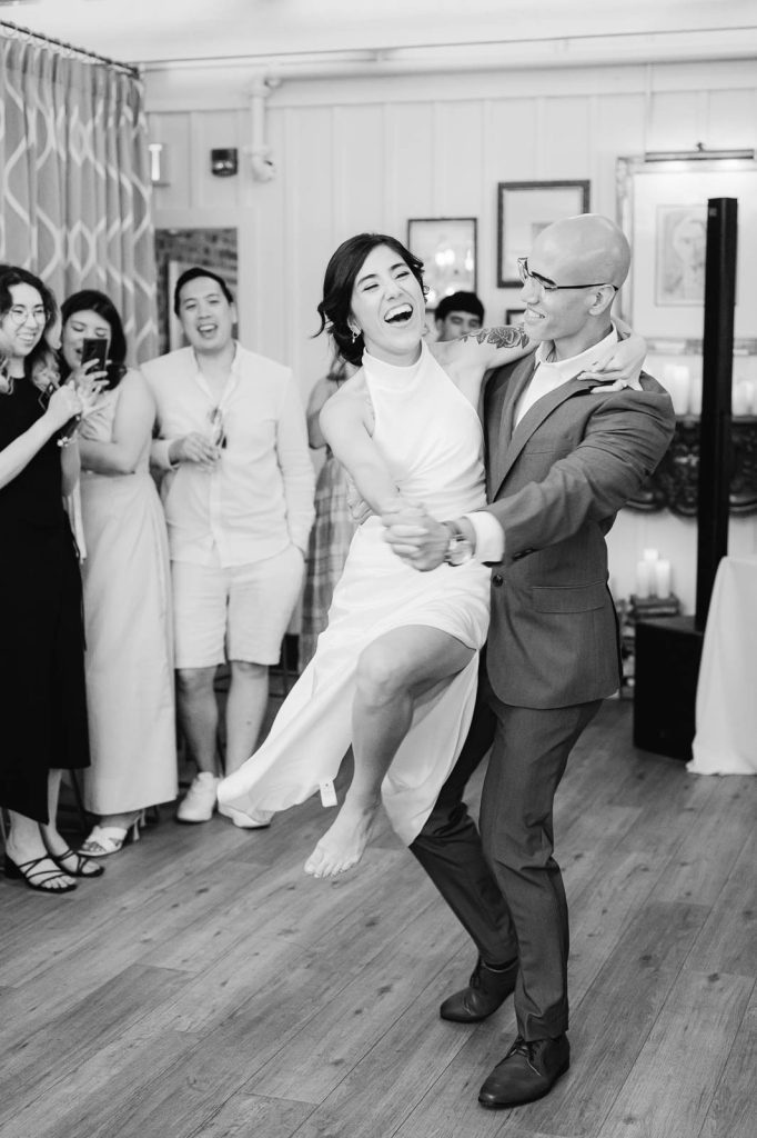 groom swings bride around during first dance at wedding reception