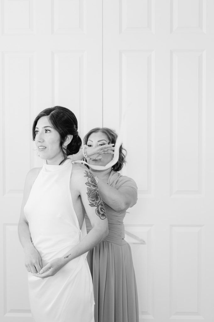 mother tying neck of bride's wedding dress