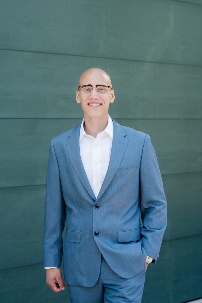 Groom portrait standing in front of green building