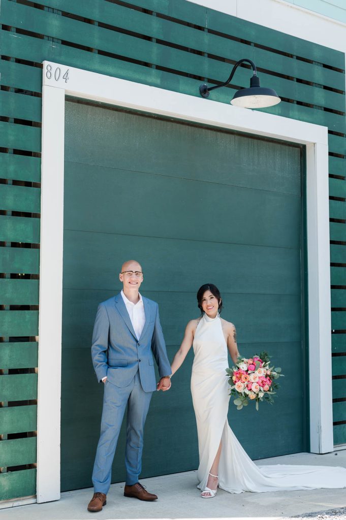 Newlyweds holding hands in front of green garage door