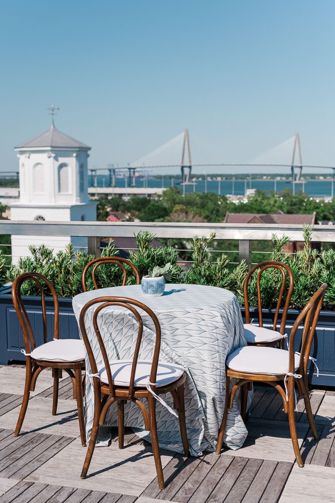 table on patio of rooftop of Dewberry hotel with view of the Ravenel Bridge