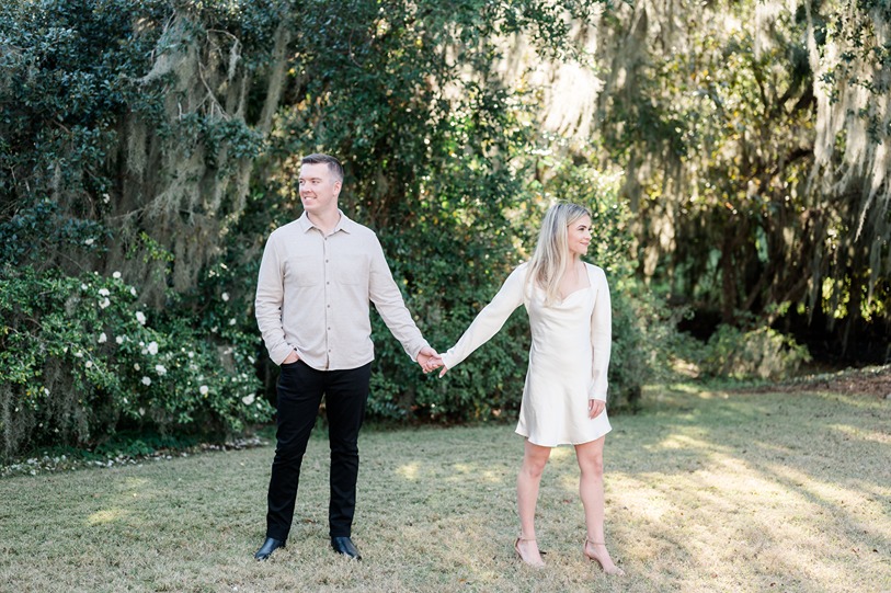Engaged couple holds hand and look opposite way