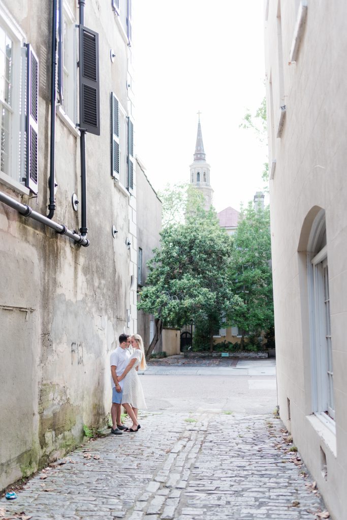 Couple kiss in alley with church steeple behind