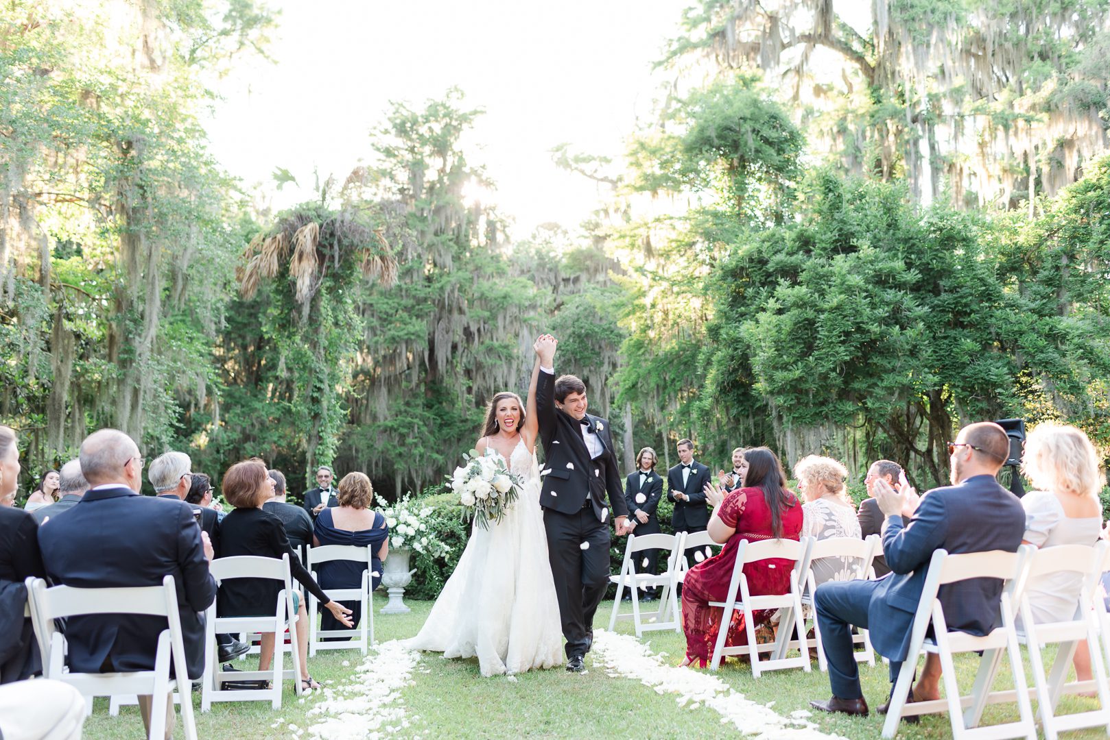 newlywed receding down aisle holding hands up in the air