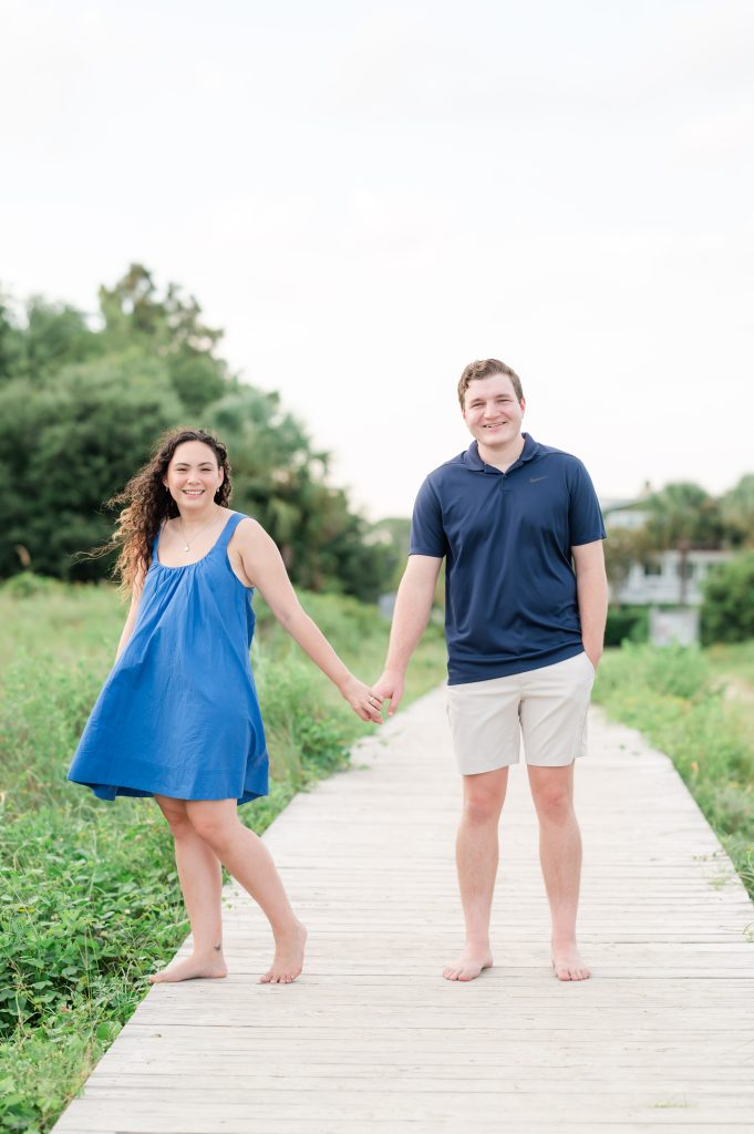 couple stand hand in hand on boardwalk after getting engaged