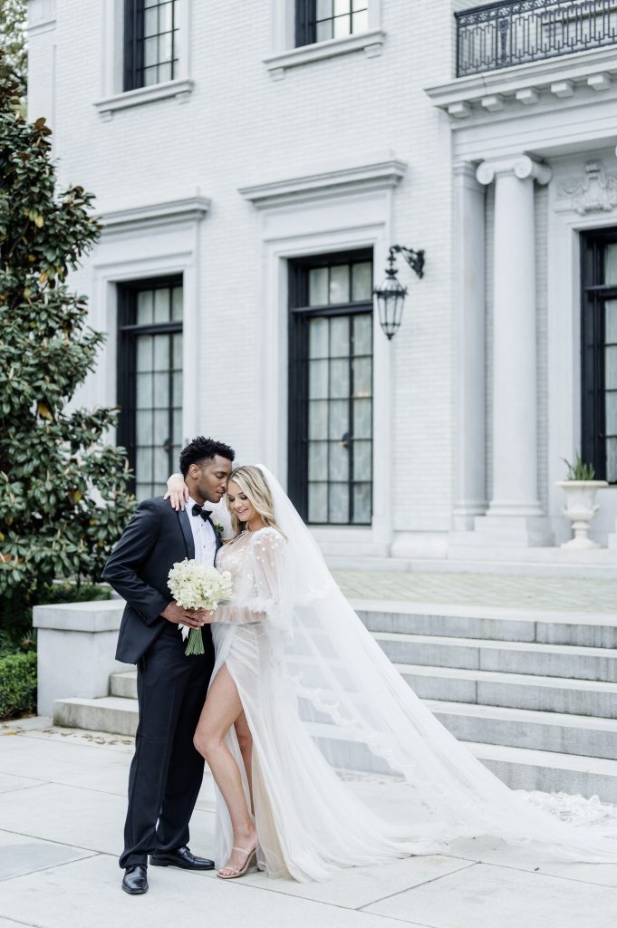 bride and groom pose in front of a mansion steps