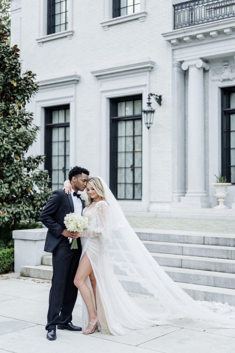 bride and groom pose in front of a mansion steps