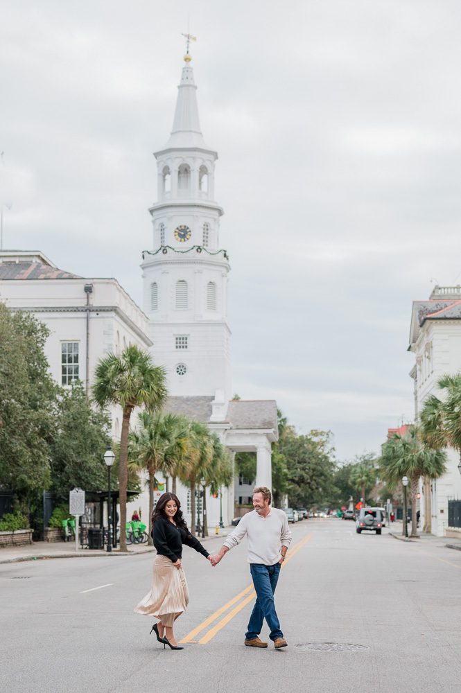 couple walking hand in hand across Charleston street
