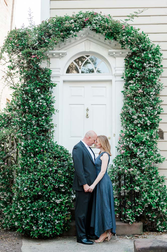 Couple leaning together in front of door surrounded by flowers
