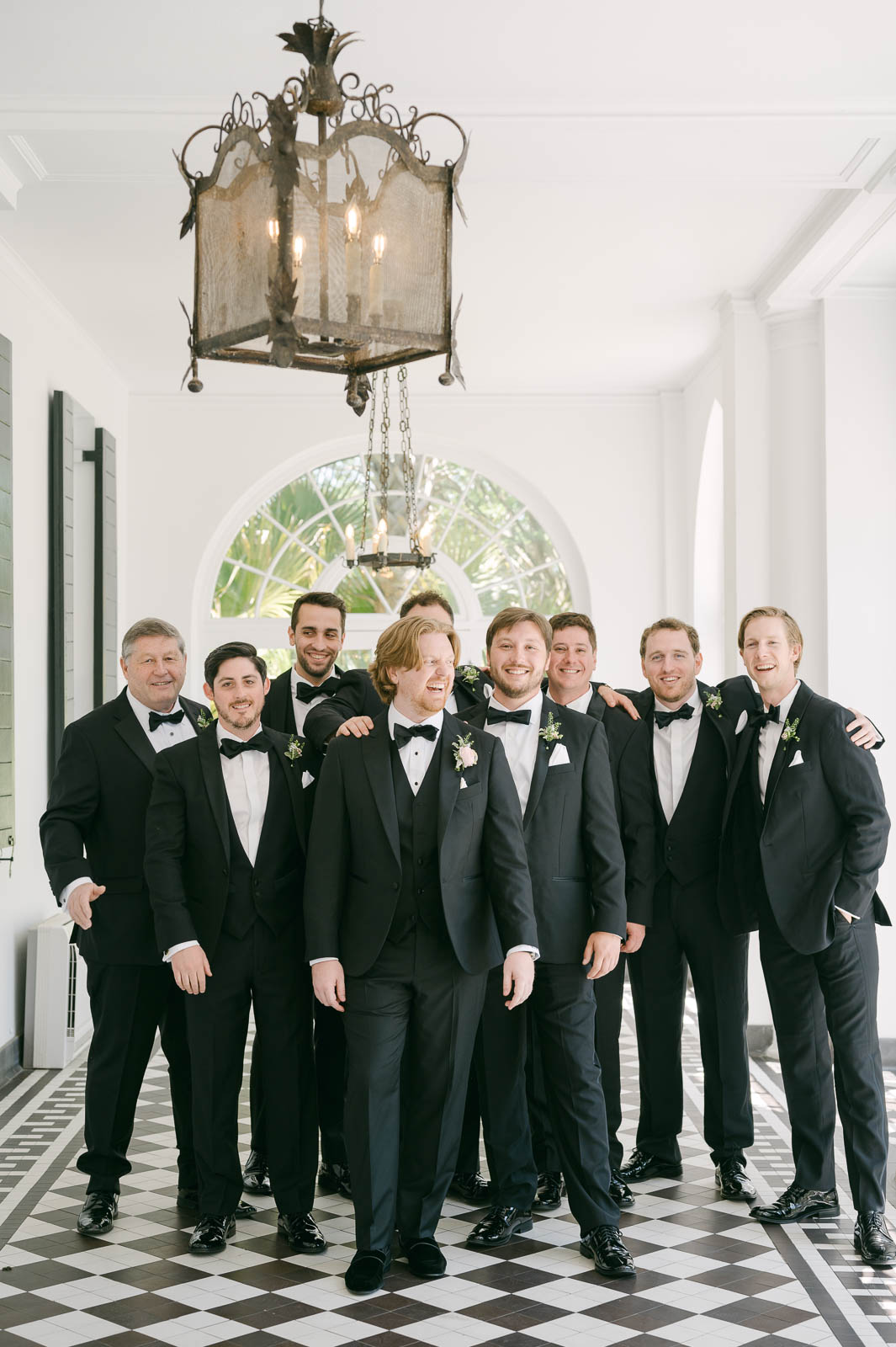 group of groomsmen in black tuxedos walking in portico of Lowndes Grove historic house