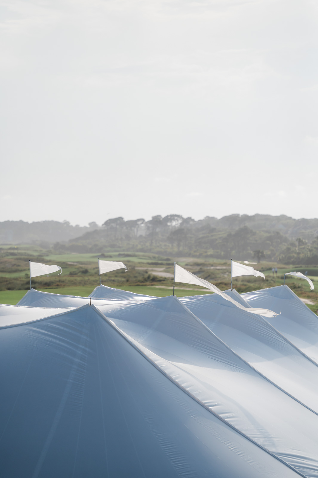 multiple white flags on top of tent blowing in the wind