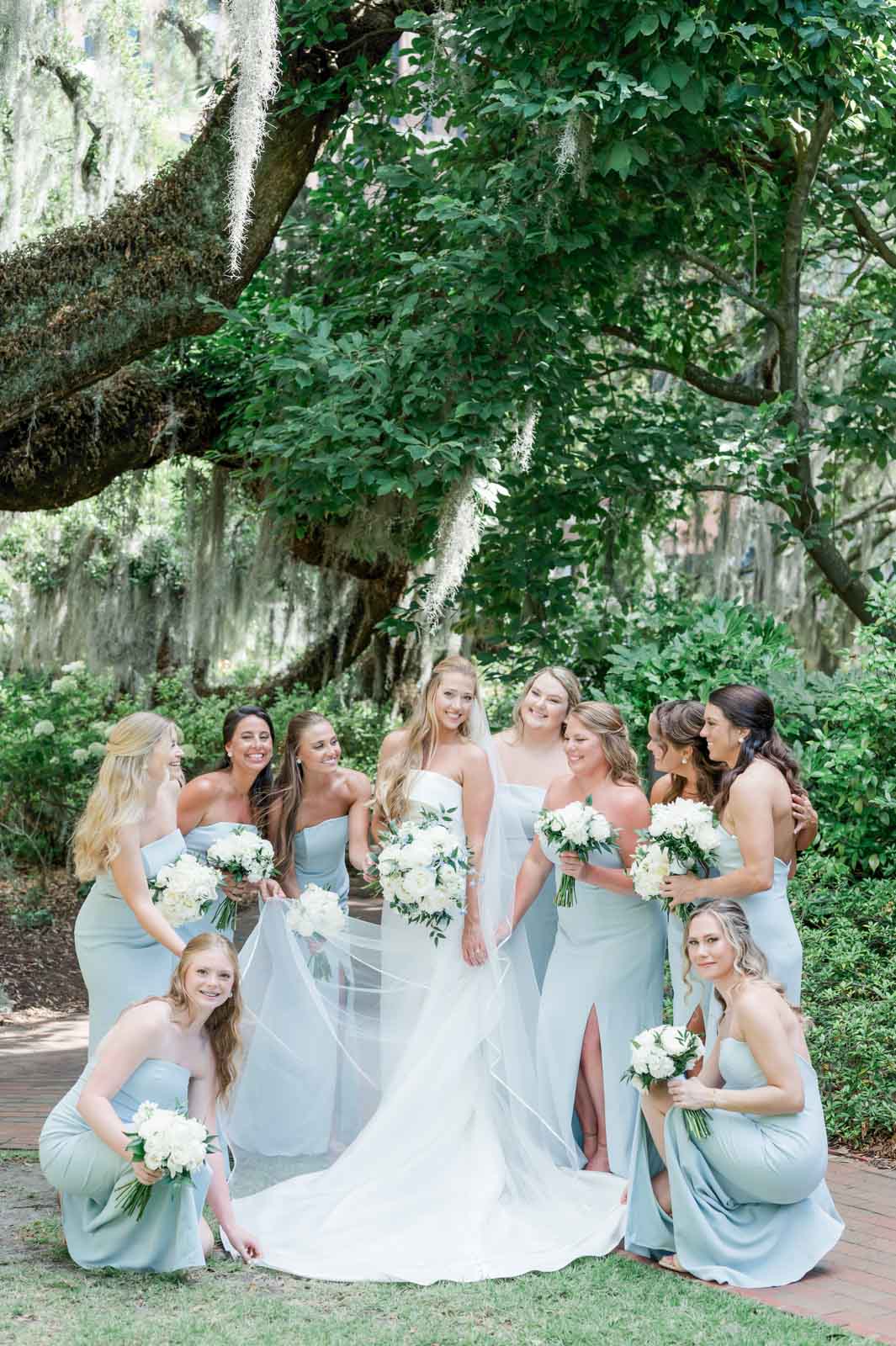bride and bridesmaids in blue dresses helping fix bride's dress